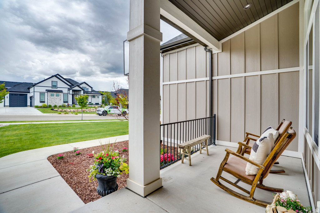 Covered front porch featuring a concrete surface, white support columns, and board-and-batten style siding