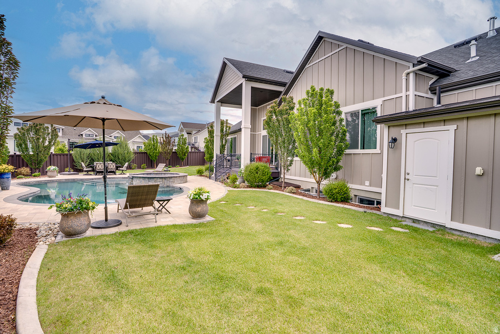 Expansive backyard featuring a curved swimming pool, integrated hot tub, surrounding paved patio, and a dedicated storage shed