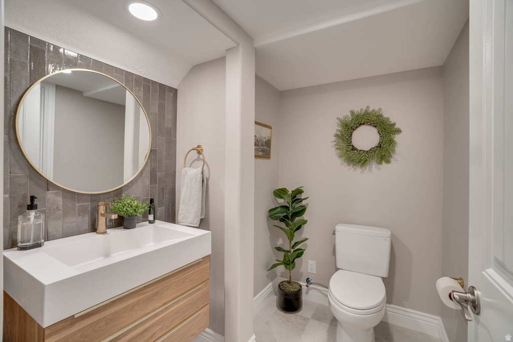 Powder room featuring a floating wood-finish vanity with an integrated white rectangular sink, a gold-finish faucet, and a circular gold-framed mirror