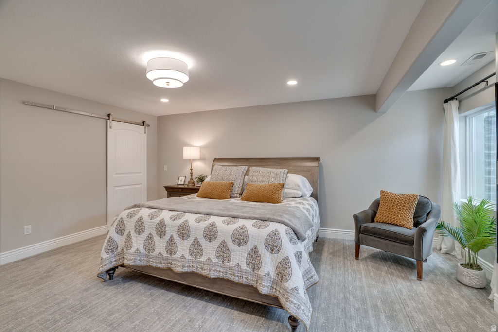 Bedroom featuring wood-finish flooring, a barn door, recessed lighting, and a window with white drapery