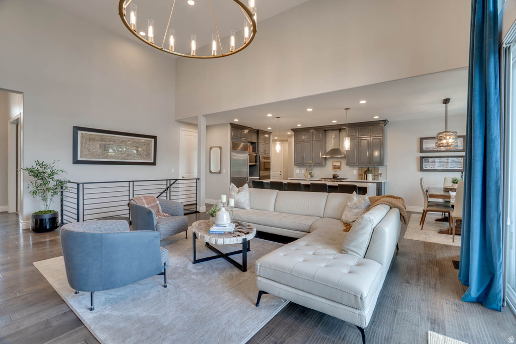 Spacious living area featuring a double-height ceiling, wood-finish flooring, and a large circular chandelier