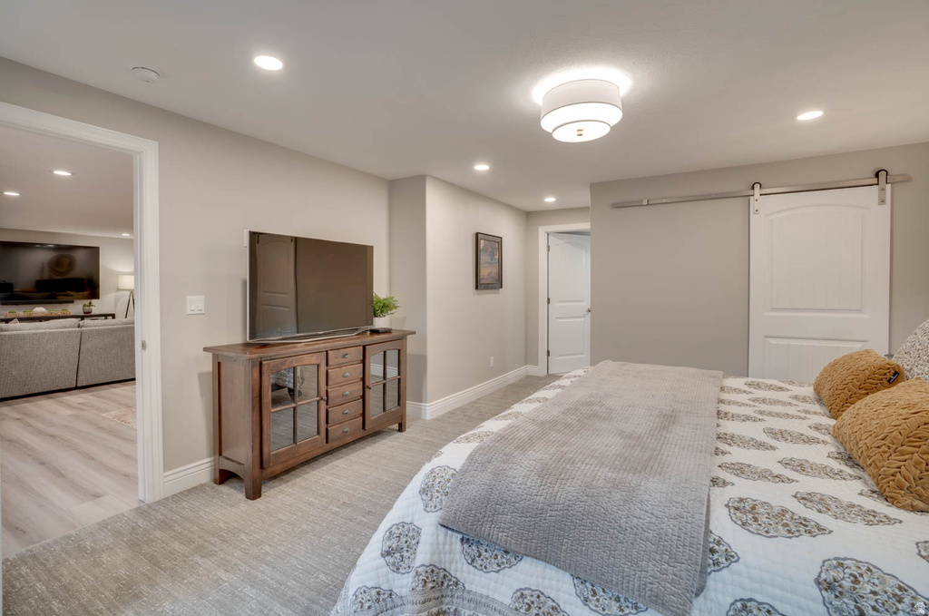Bedroom featuring recessed lighting, a ceiling-mounted light fixture, light gray carpeting, a white barn door, and a white interior door