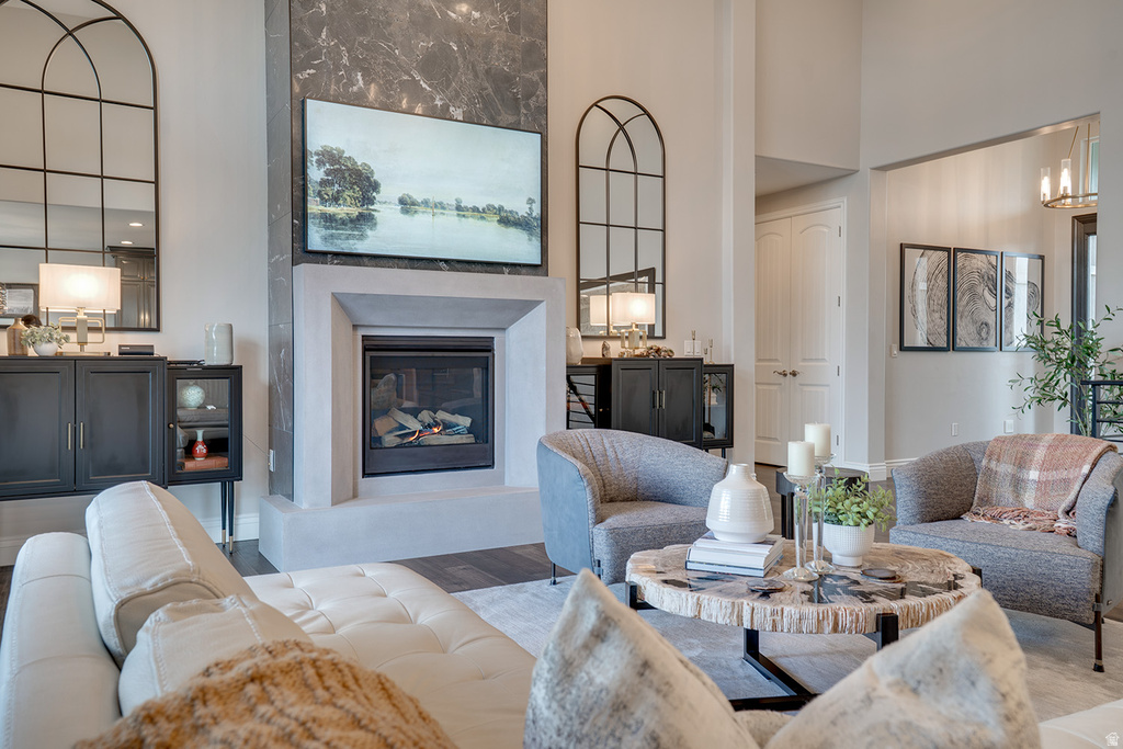 Living area featuring a floor-to-ceiling fireplace with a stone surround and integrated hearth, dark wood-finish flooring, and high ceilings
