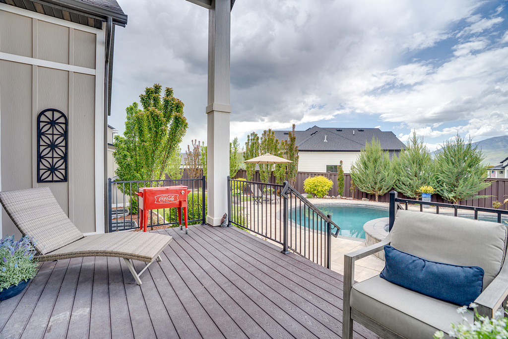 Expansive outdoor deck featuring wood-finish decking, a black metal railing, and direct access to a swimming pool