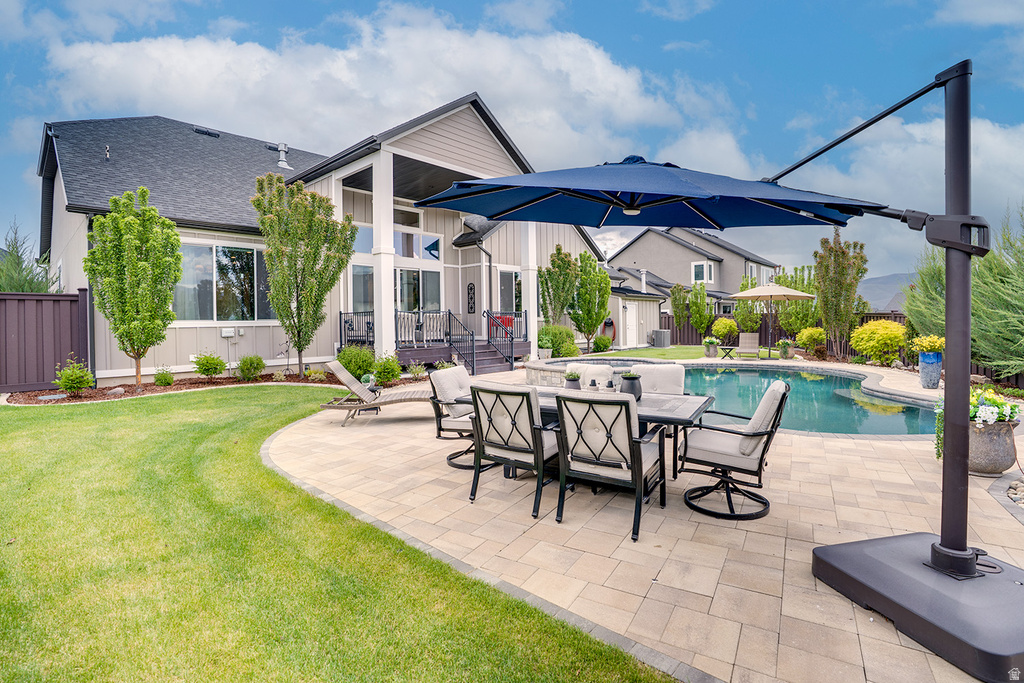 Expansive outdoor living area featuring a patterned paver patio, in-ground swimming pool, and a landscaped yard