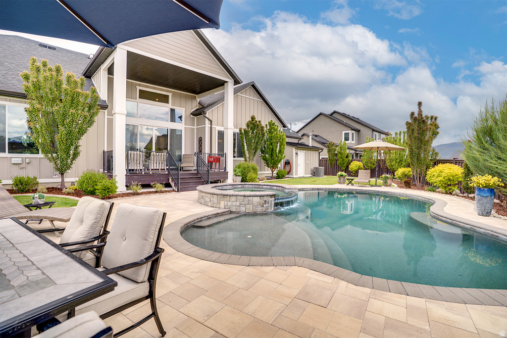 Expansive patio featuring a built-in swimming pool and adjacent hot tub, complemented by a covered outdoor living area with a balcony