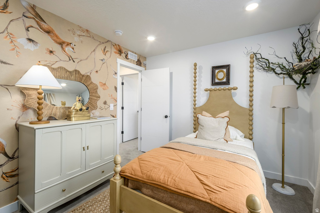 Recessed lighting illuminates a room featuring an accent wall with custom wallpaper