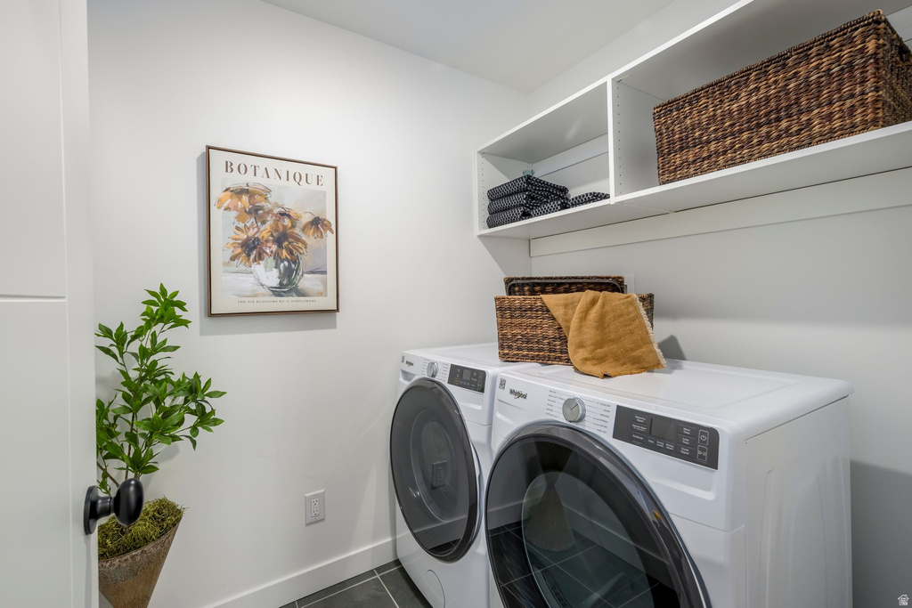 Laundry area featuring a side-by-side washer and dryer, open shelving, and dark-toned flooring