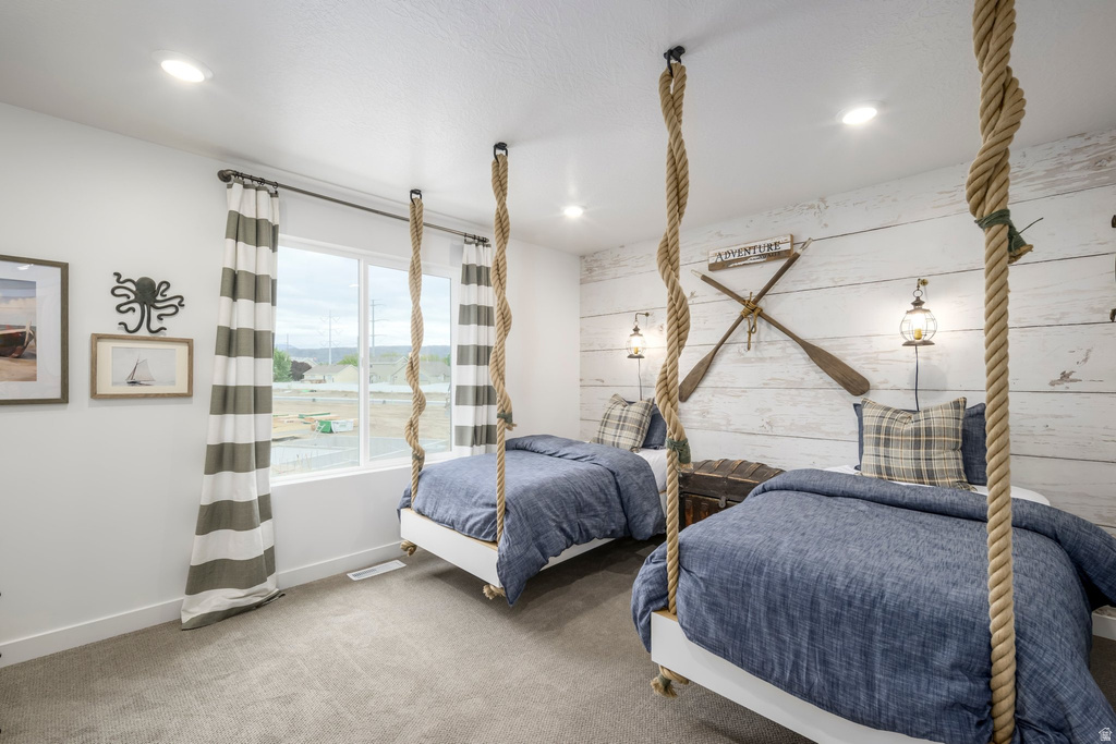 Recessed lighting illuminates a room featuring two built-in suspended beds with rope accents