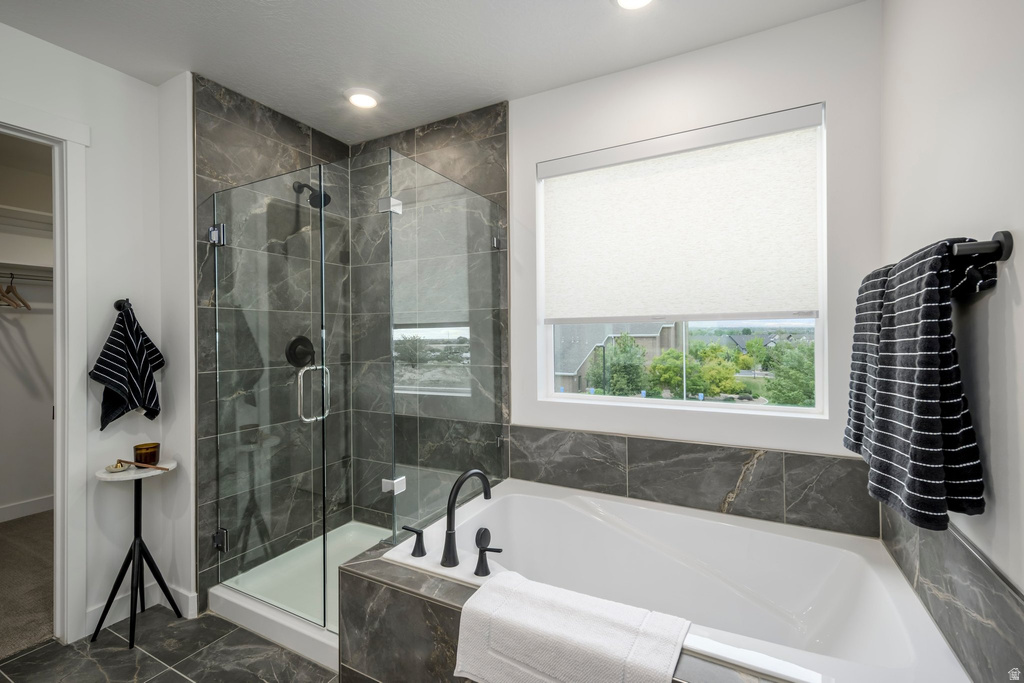 Freestanding soaking tub with dark stone surround, walk-in glass shower enclosure, and matte black fixtures
