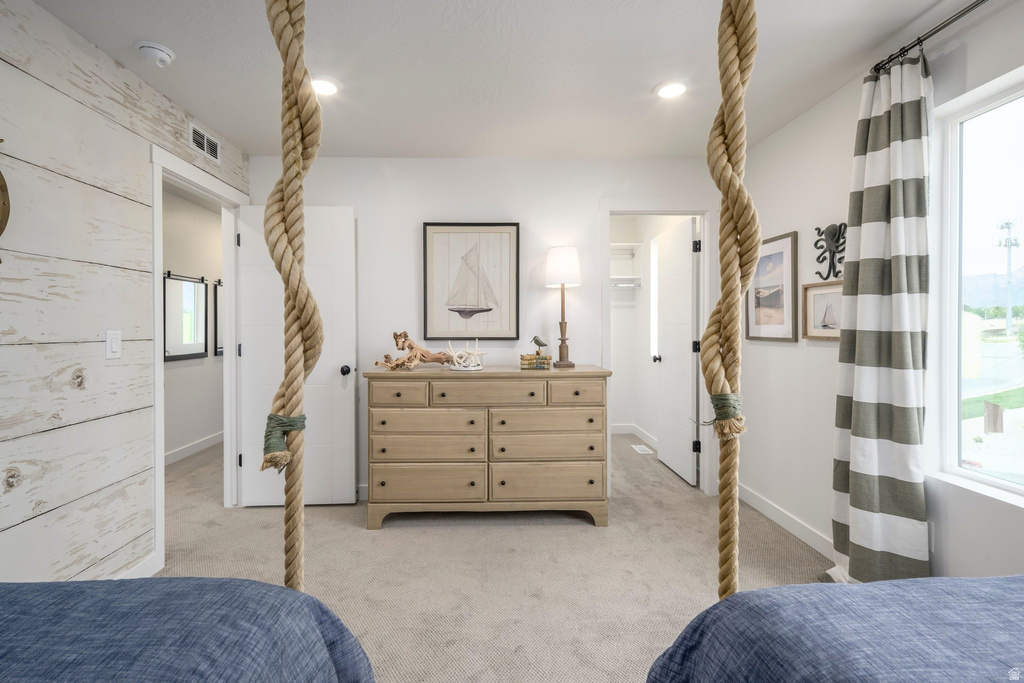 Bright interior room featuring a decorative rope element, light-colored carpeting, and a shiplap accent wall