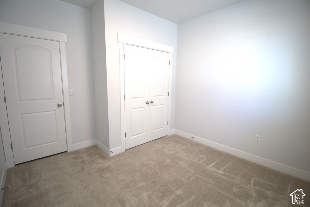 Neutral tone wall color with white trim, light-colored carpet, and bi-fold closet doors
