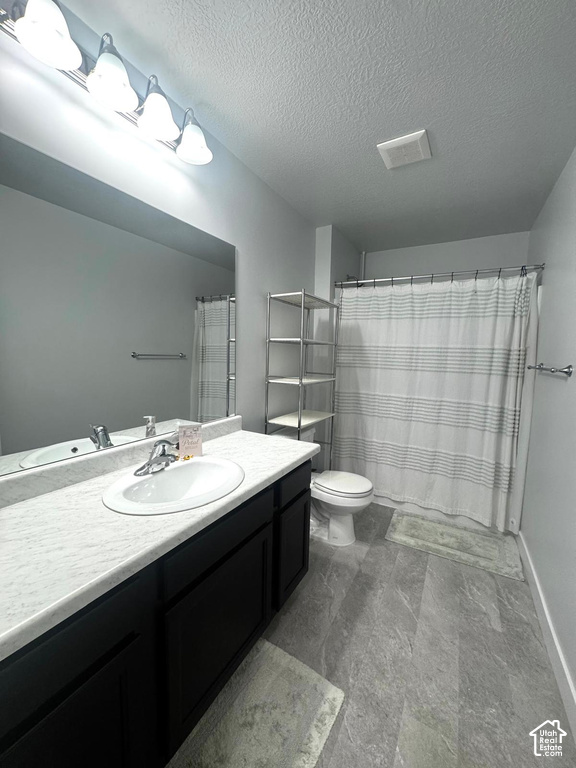 Bathroom featuring a single vanity with dark cabinetry, integrated sink, and light-colored countertop