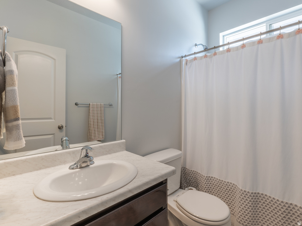 Bathroom featuring a vanity with an integrated sink and light-toned countertop, a rectangular mirror, and a window for natural light