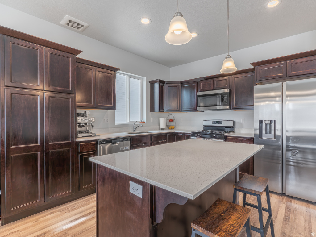 Kitchen featuring wood-finish flooring, dark wood cabinetry, and a light-toned countertop island