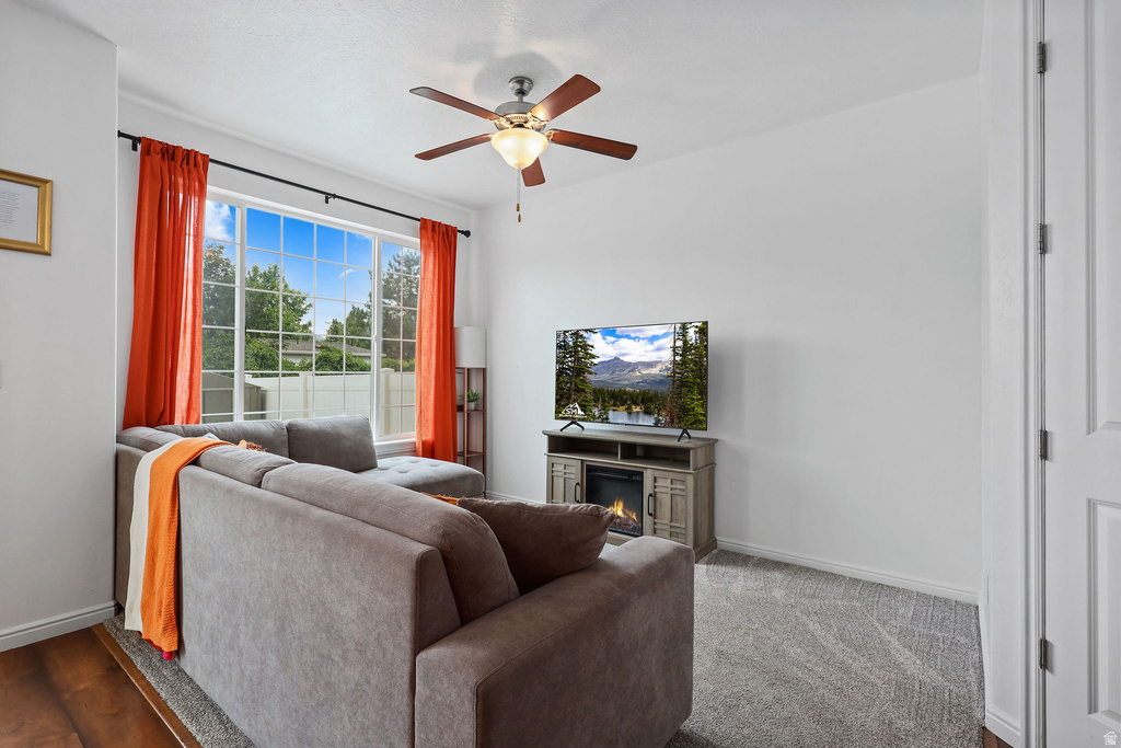 Bright interior space featuring a large picture window, ceiling fan, and wood-finish flooring