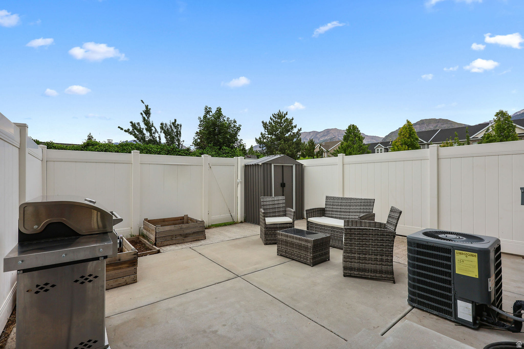 Concrete patio featuring a privacy fence, storage shed, and planter boxes