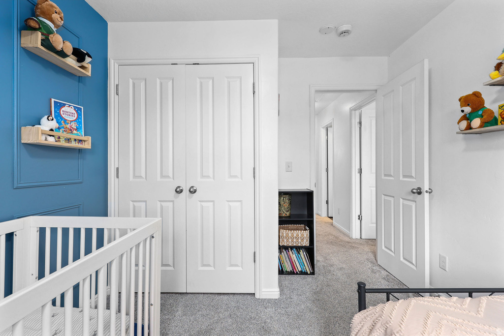 Carpeted room featuring a paneled accent wall, bi-fold closet doors, and a doorway leading to a hallway