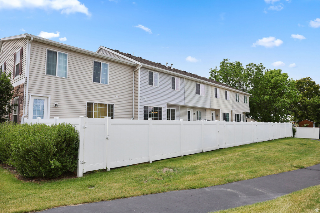 Exterior siding finish with stone accents, multiple windows, and a white privacy fence