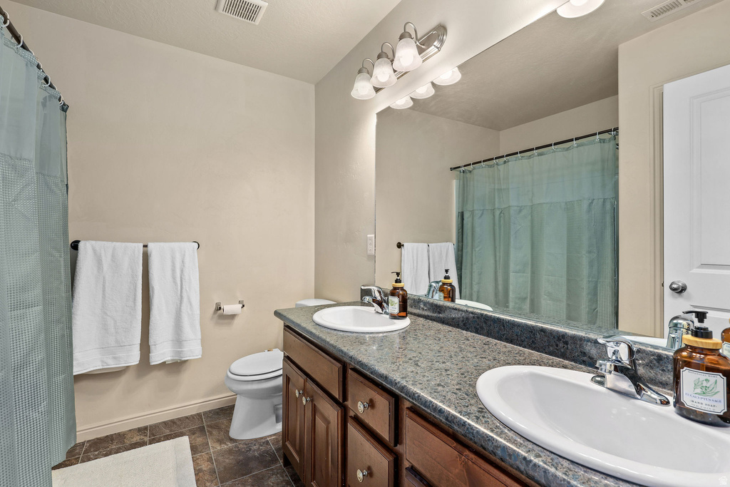 Bathroom featuring a double vanity with integrated sinks, granite-finish countertop, and wood-finish cabinetry
