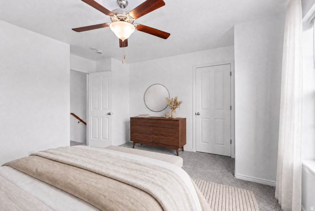Carpeted room featuring a ceiling fan with light fixture, white interior doors, and a window with sheer curtains