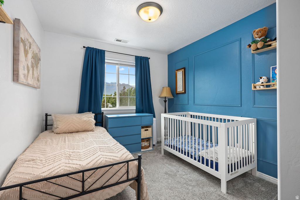 Room featuring a contrasting accent wall with applied molding, a double-paned window with blue drapery, wall-to-wall carpeting, and a flush mount ceiling light