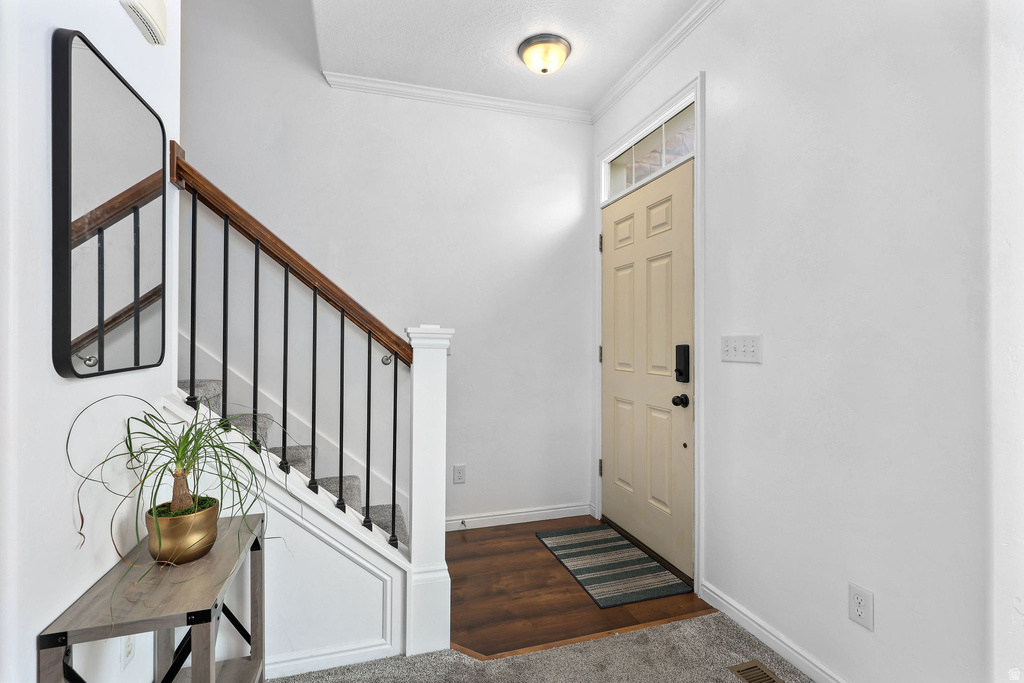 Entryway featuring a light-colored door with transom window, wood-finish flooring, and a staircase with a dark wood handrail and black metal balusters