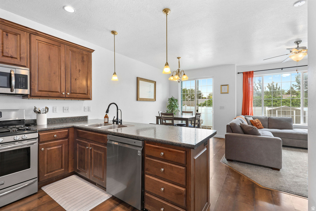 Open-concept living area featuring a kitchen island with stone countertops, stainless steel appliances, and rich wood cabinetry