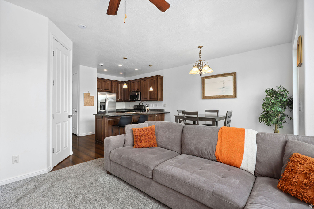 Open-concept living area featuring light gray carpeting and a ceiling fan