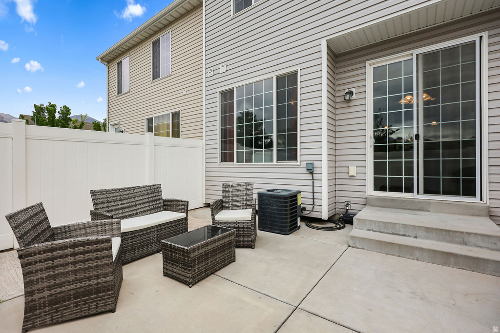 Concrete patio with a white vinyl privacy fence, full-light grid-pattern sliding glass door, and a multi-pane window