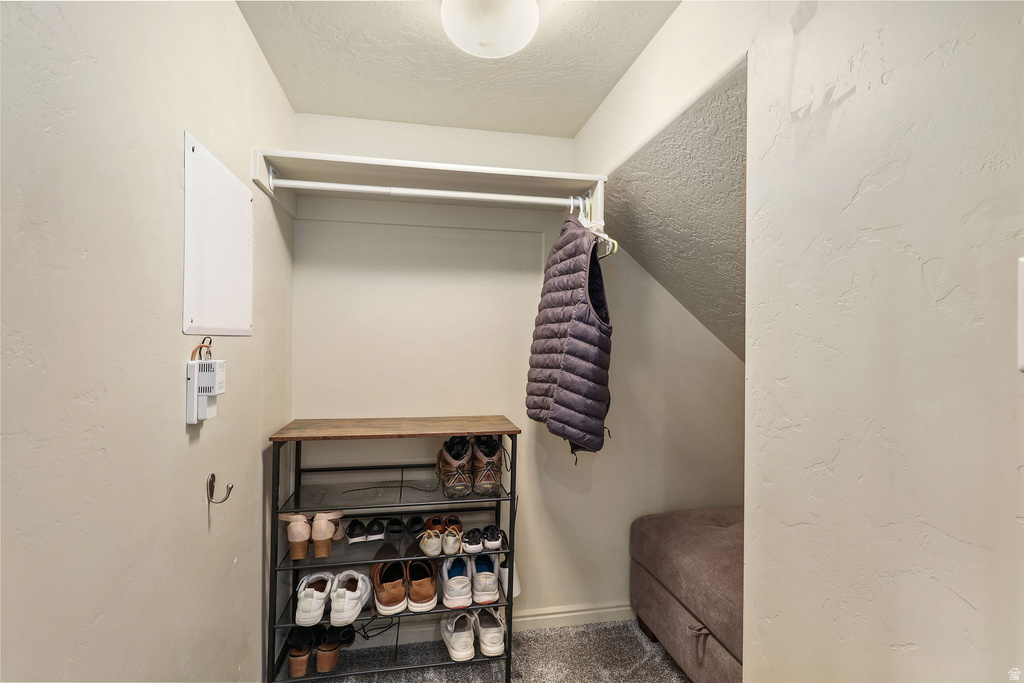 Compact closet space with a built-in hanging rod, overhead shelf, and textured wall finish