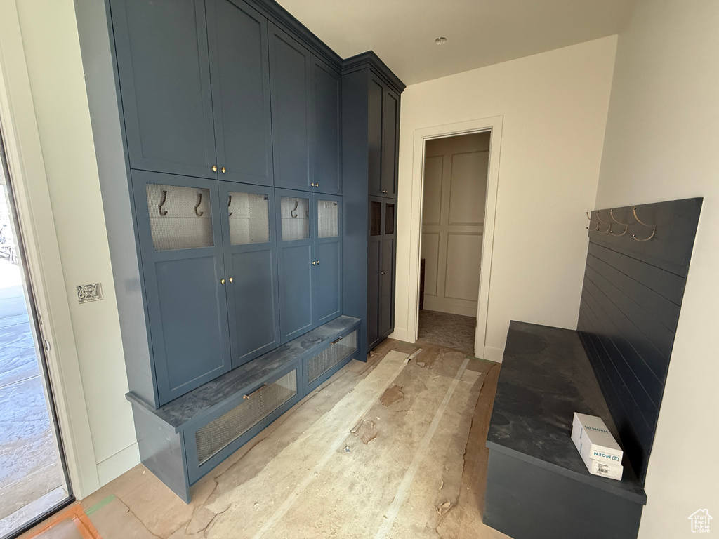 Built-in cabinetry with brass hardware, open shelving with hooks, integrated bench seating, and an additional built-in bench with a slatted backrest