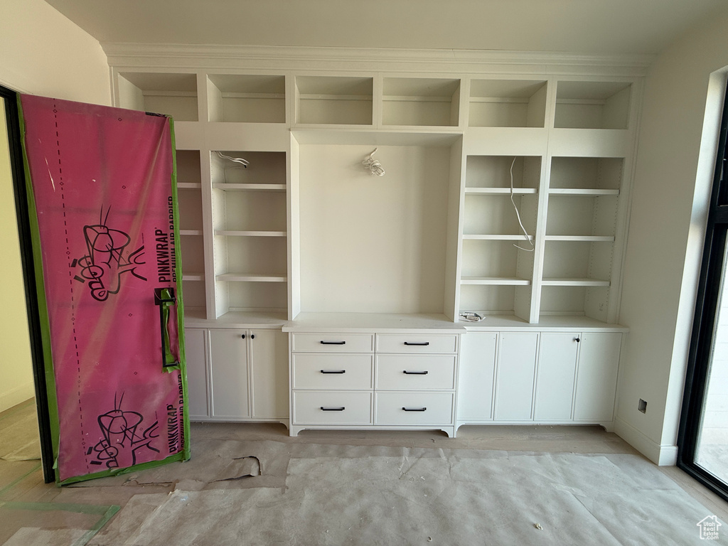 Built-in custom cabinetry with shaker-style doors and drawers, extensive shelving, and crown molding