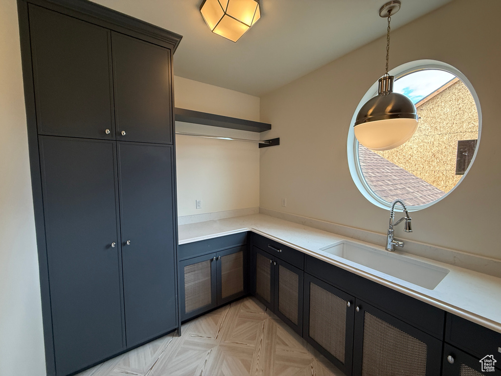 Built-in cabinetry with paneled doors, stone-finish countertops, undermount sink with gooseneck faucet, circular window, and patterned tile flooring