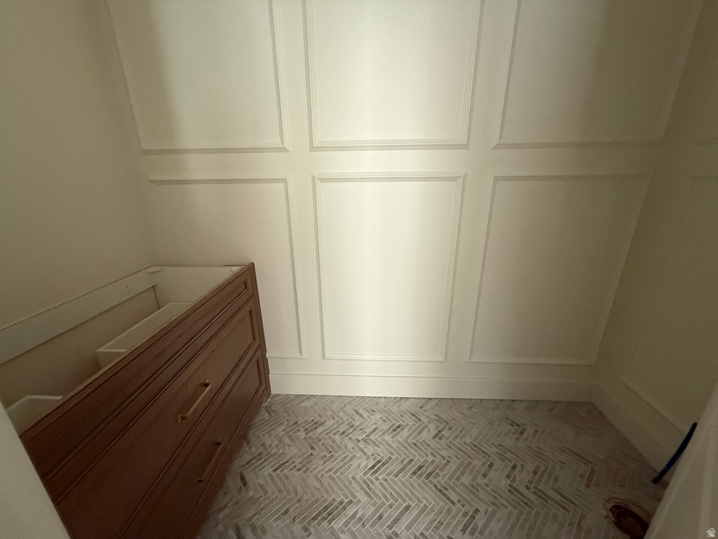 Paneled wall detailing, light-toned flooring in a herringbone pattern, and a wood-finish vanity with drawer storage