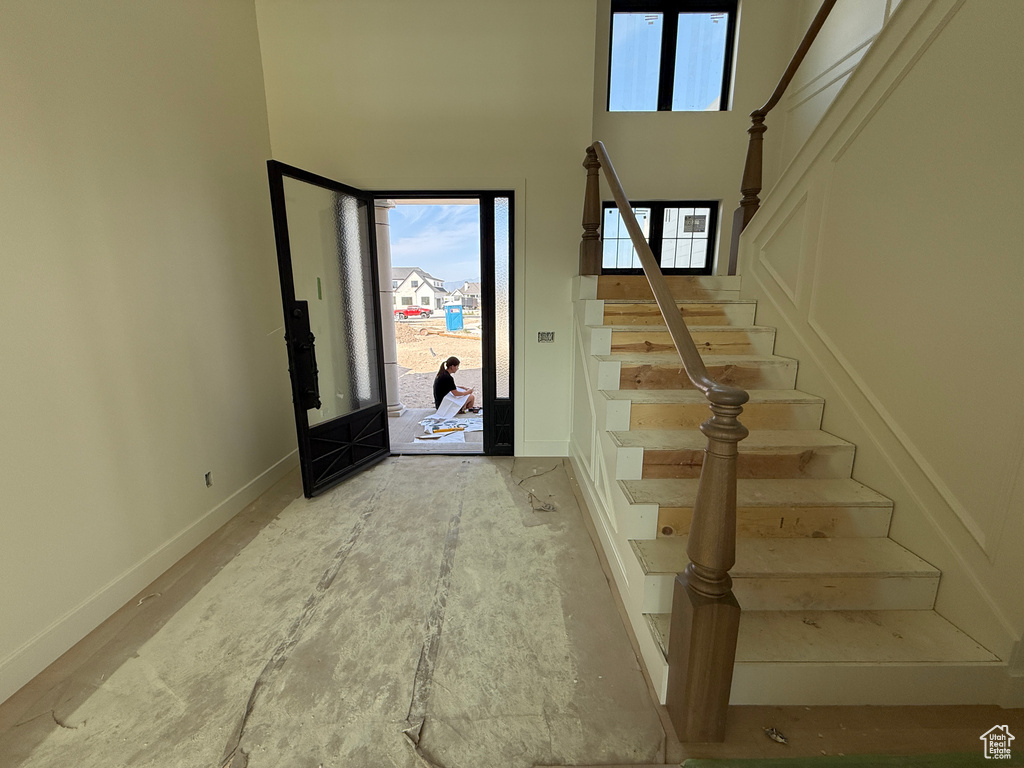 Two-story entry with a wood-finish staircase and balustrade, wall paneling, and an ornate dark-frame glass door