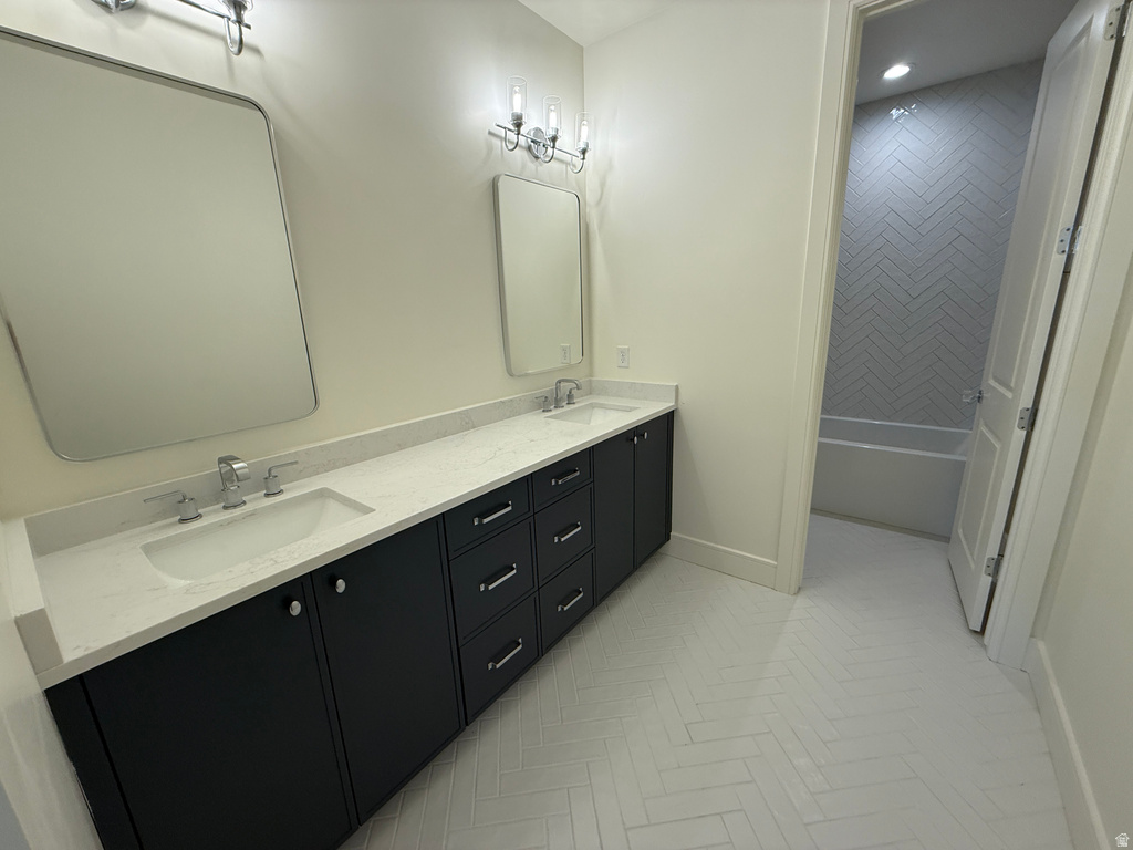 Dual vanity with undermount sinks and chrome fixtures, light-toned countertop, dark wood-finish cabinetry, and white herringbone-patterned tile flooring
