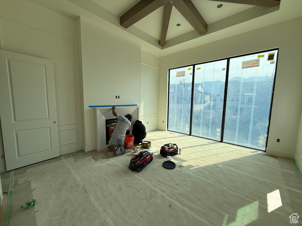 Coffer ceiling with exposed beams, floor-to-ceiling windows, fireplace, and paneled walls