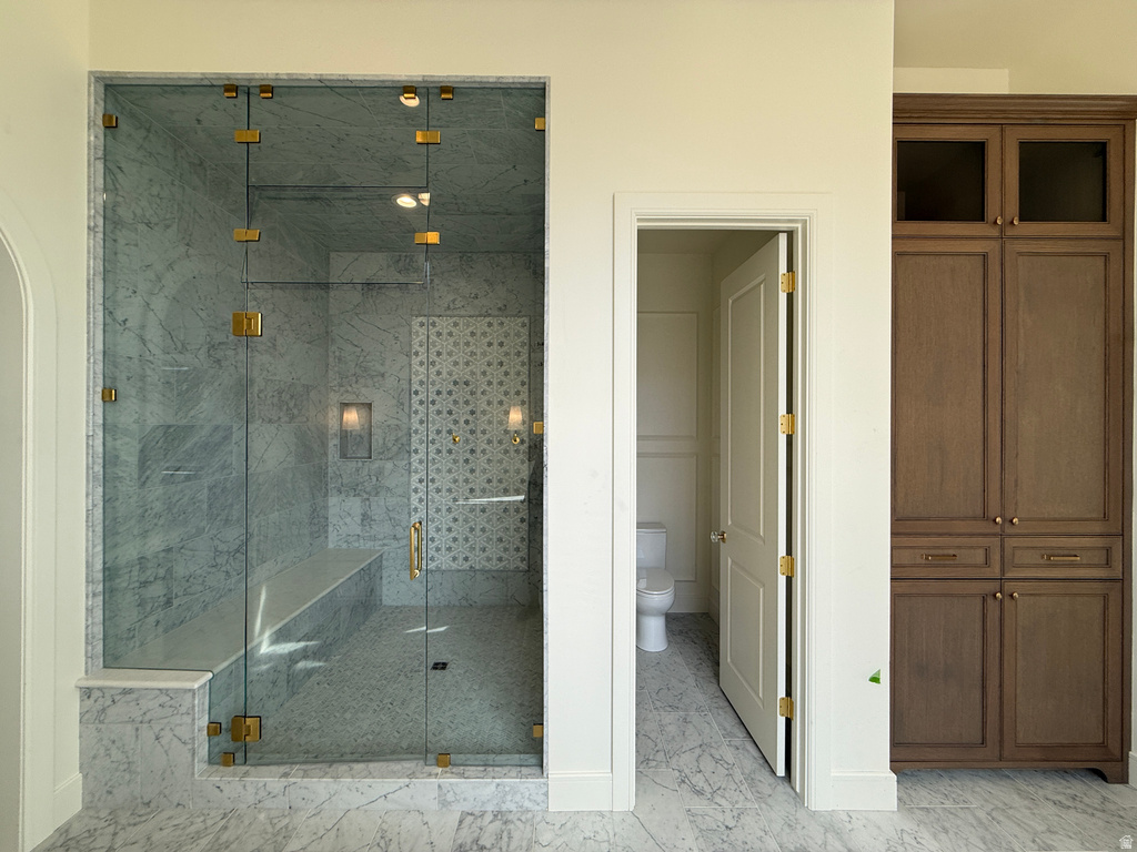 Glass-enclosed shower with polished brass hardware, a built-in bench, and varied tile finishes
