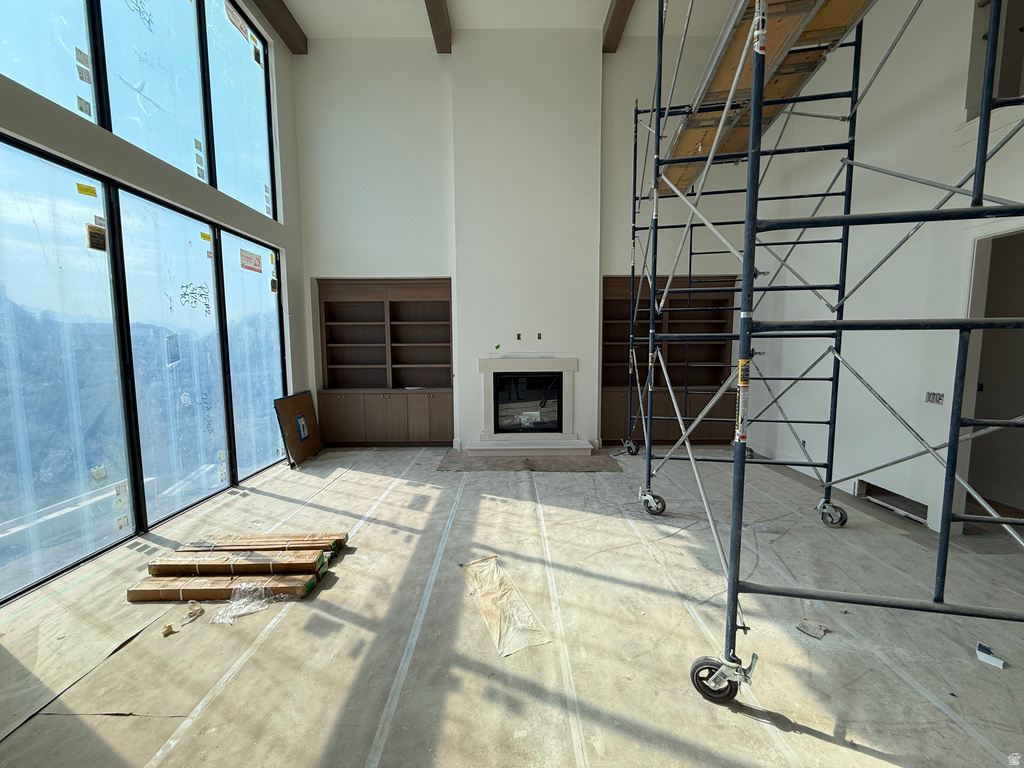 Expansive windows, high ceilings with exposed beams, built-in shelving, and a stone-surround fireplace