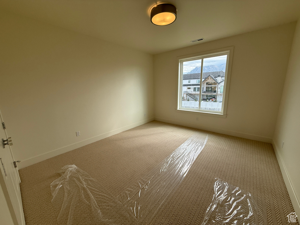 Spacious room featuring neutral wall paint, patterned carpet flooring, a large window, and a drum ceiling light fixture