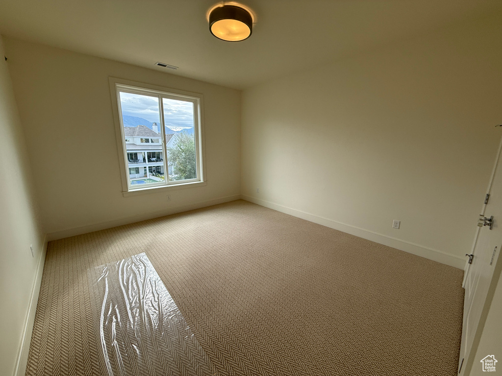 Spacious room featuring a large window, neutral wall paint, patterned carpeting, and a flush mount ceiling light