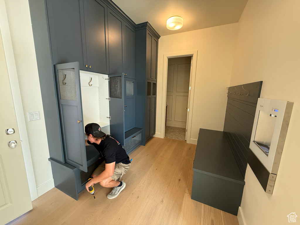 Light wood-finish flooring, built-in storage cabinetry, integrated bench seating, and a wall-mounted water dispenser