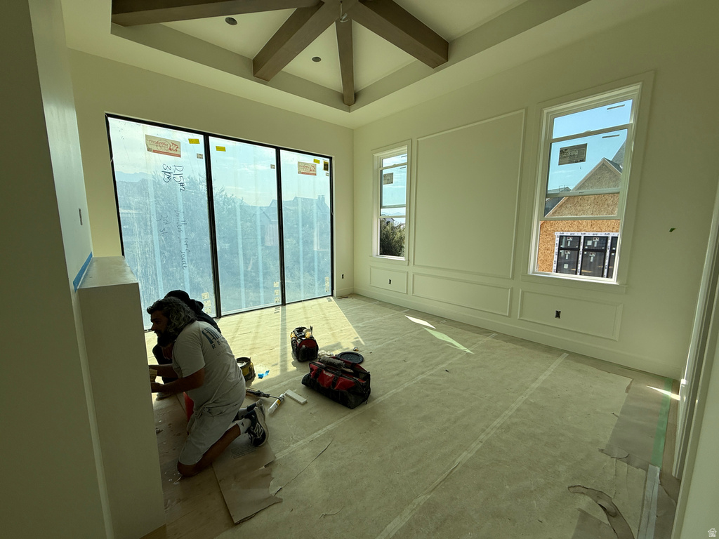 Tray ceiling with exposed wood-finish beams, expansive floor-to-ceiling windows, and decorative wall molding