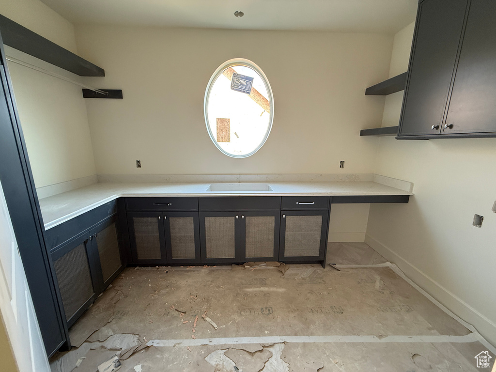 Oval window, extensive countertop space, integrated sink, dark wood-finish cabinetry, and open shelving