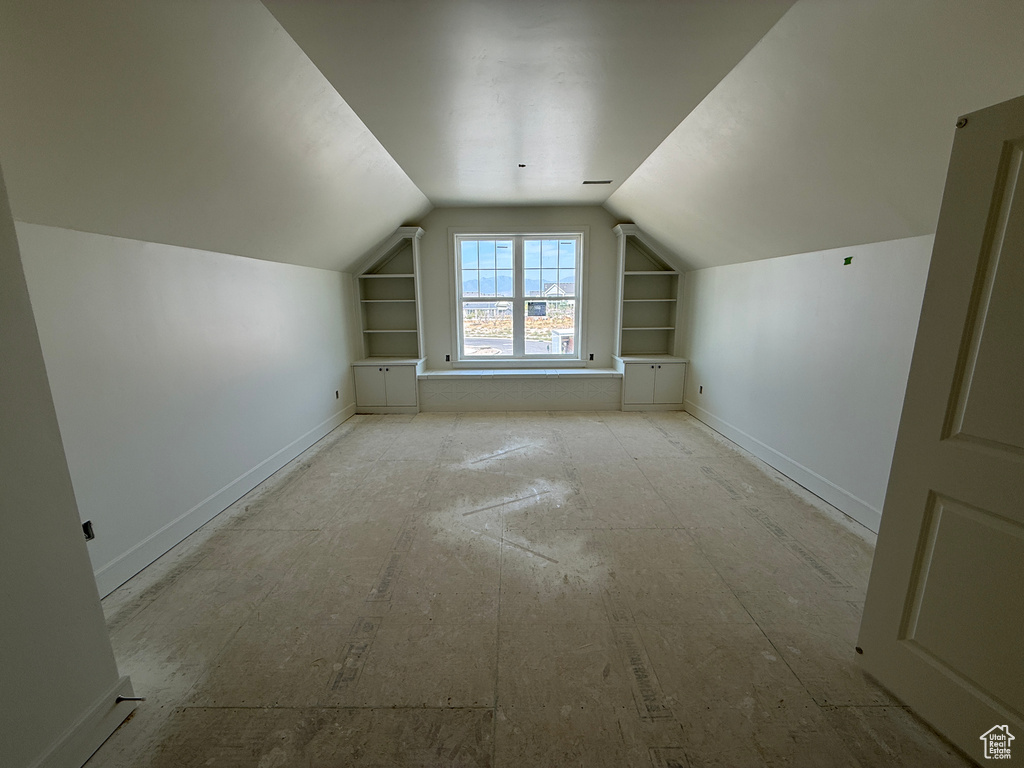 Window seat with built-in storage, symmetrical built-in shelving, attic ceiling, and a paneled interior door