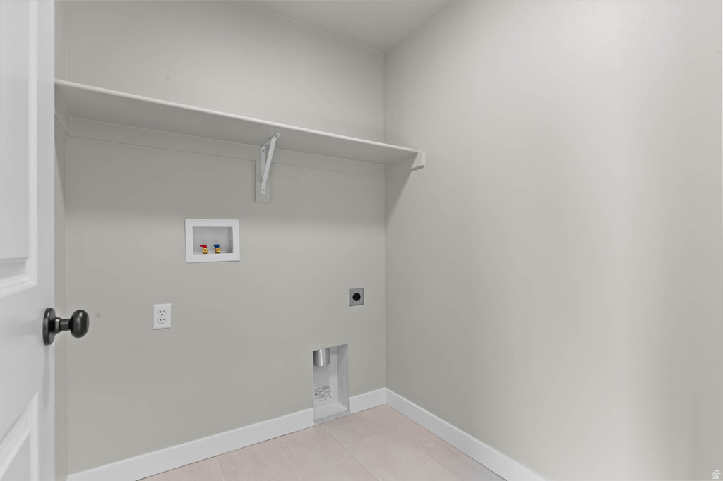 Dedicated utility space featuring a neutral color palette, integrated wall shelving, electrical outlets, and plumbing connections