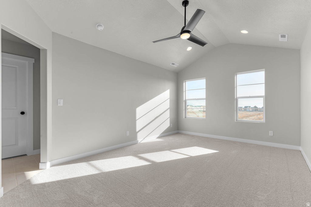 Spacious room featuring vaulted ceilings, a ceiling fan with integrated lighting, recessed lighting, two windows, and neutral carpet flooring