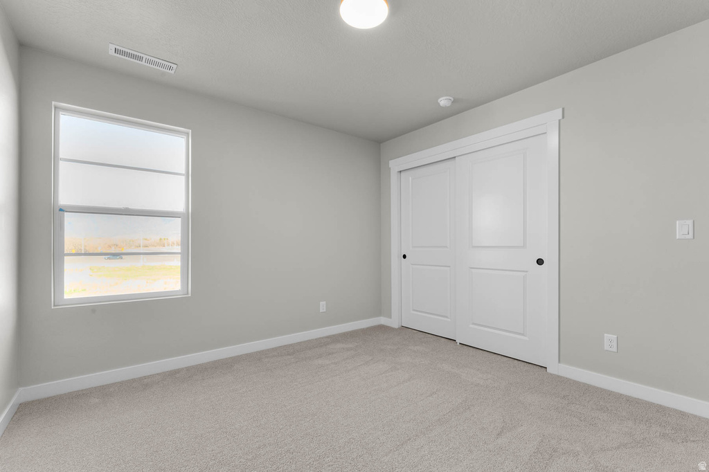 Neutral wall paint with coordinating light carpet flooring, white trim, and a window with a white frame