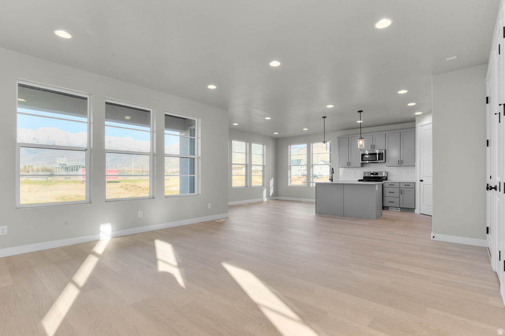 Open-concept living area with light wood-finish flooring, recessed lighting, and expansive windows